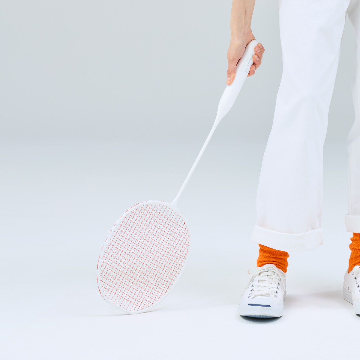 白くシンプルなyocabitoのバドミントンラケットVALENCIA。軽やかで、おしゃれなデザインを笑顔で表現する女性。